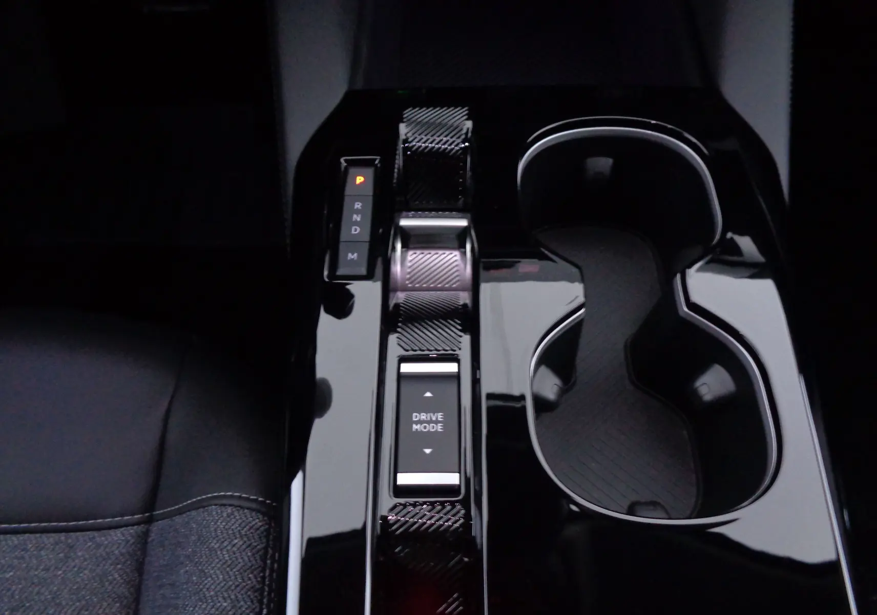 Gros plan sur la console centrale noire brillante de la Citroën C5 X 2023, avec sélecteur de boîte auto et porte-gobelets.