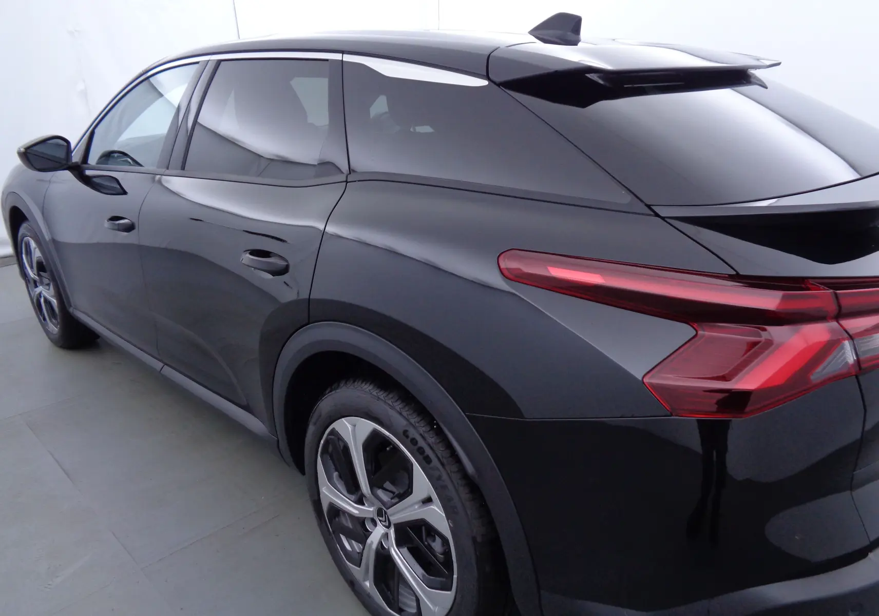 Vue 3/4 arrière droite d'une Citroën C5 X noire métal avec feux arrière LED et jantes bi-ton de 19 pouces.