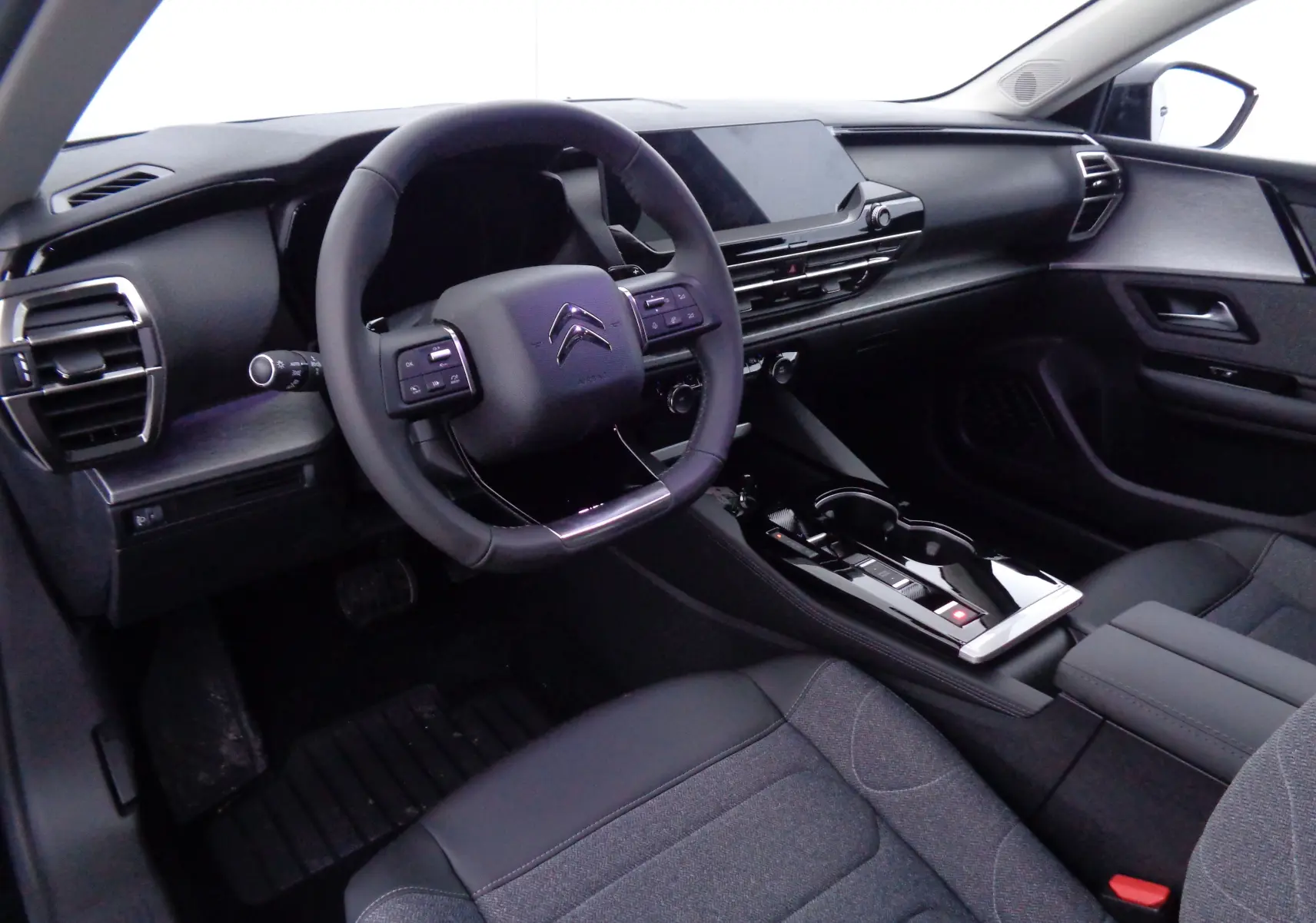 Vue intérieure côté conducteur du Citroën C5 X 2023, tableau de bord noir avec volant multifonction et console centrale moderne.