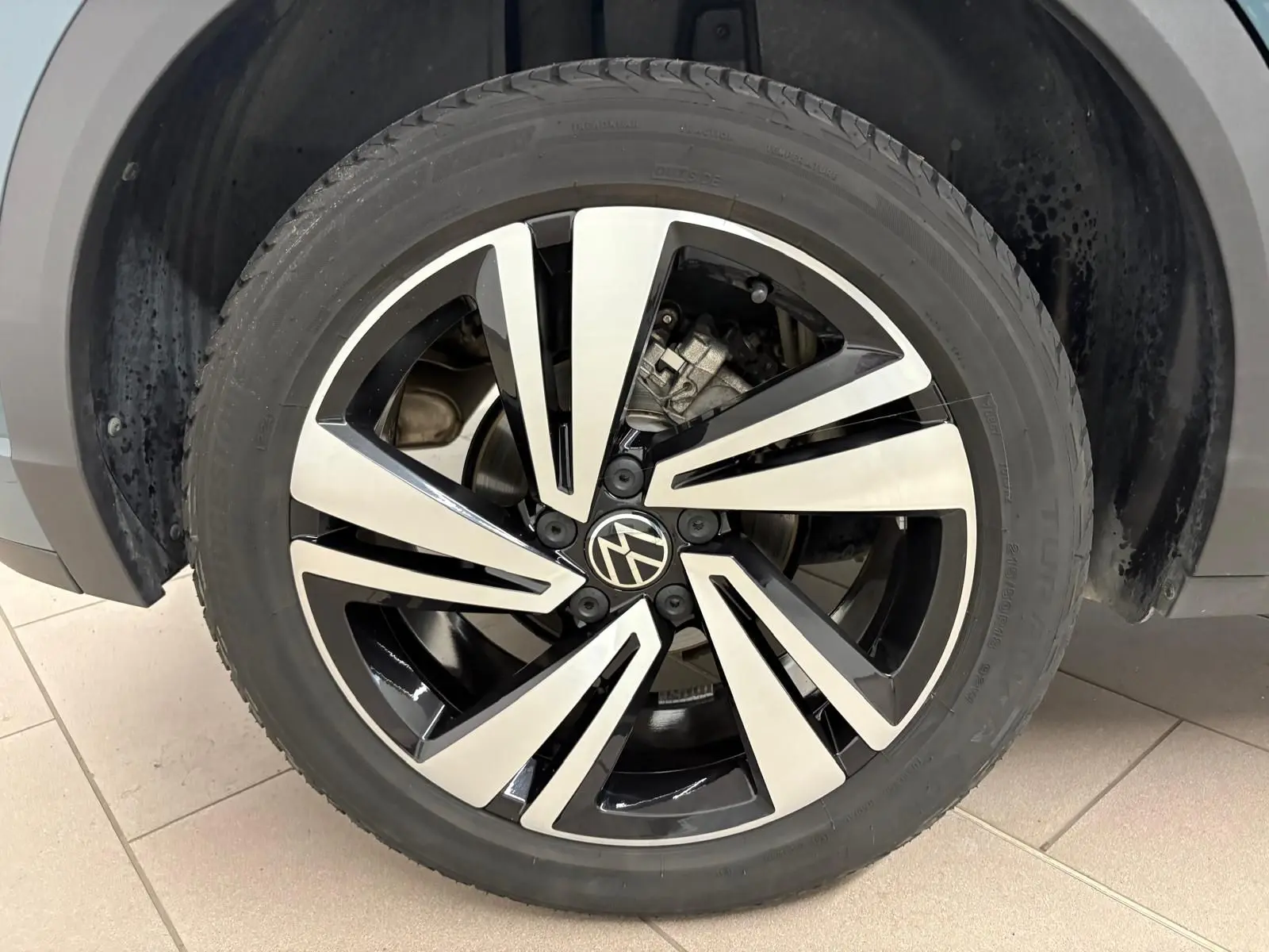 Gros plan sur la jante alliage bicolore du Volkswagen T-Roc 2024 bleu pétrole, version R-Line avec logo VW central.