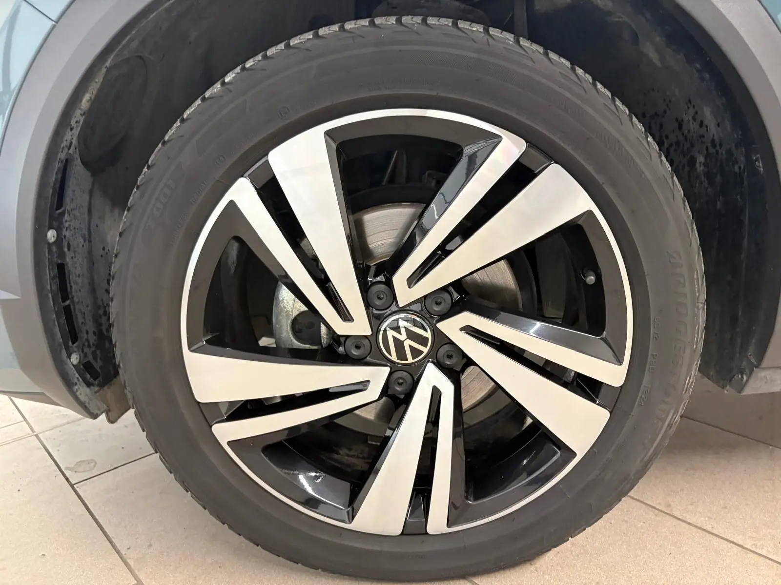 Gros plan sur la jante alliage bicolore du Volkswagen T-Roc 2024, version R-Line, avec logo VW au centre.