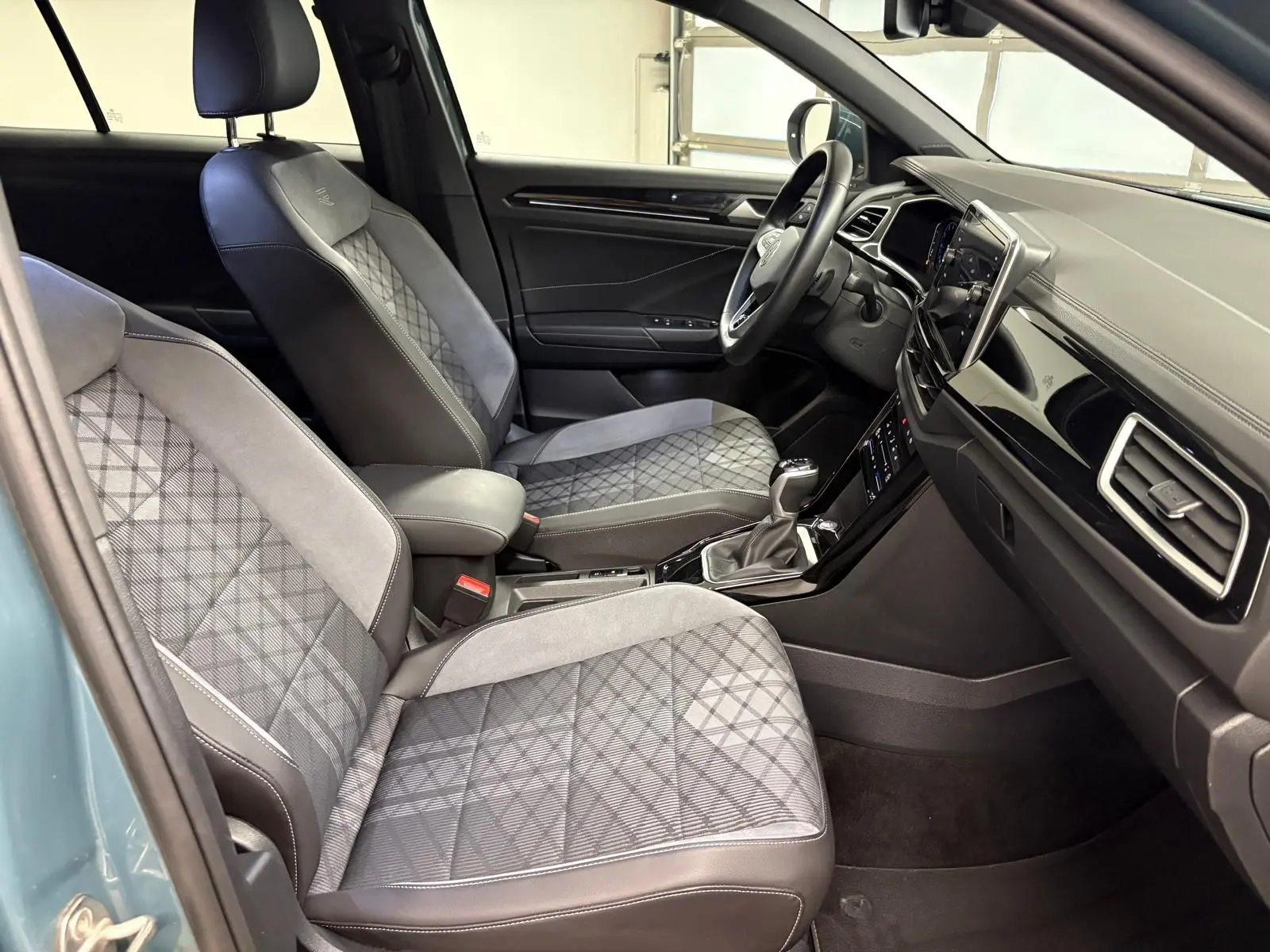 Vue intérieure côté conducteur du Volkswagen T-Roc 1.5 TSI R-Line 2024 avec sièges tissu et alcantara gris à motifs géométriques.