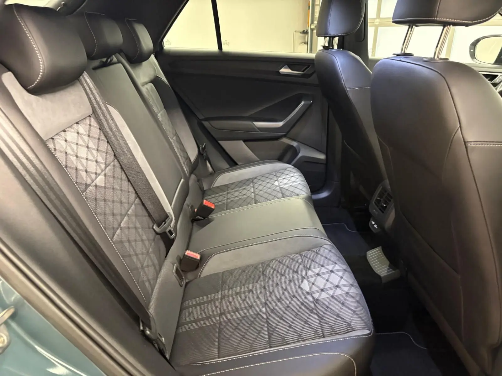 Vue intérieure des sièges arrière en tissu et cuir noir avec surpiqûres, Volkswagen T-Roc 2024 bleu pétrole.