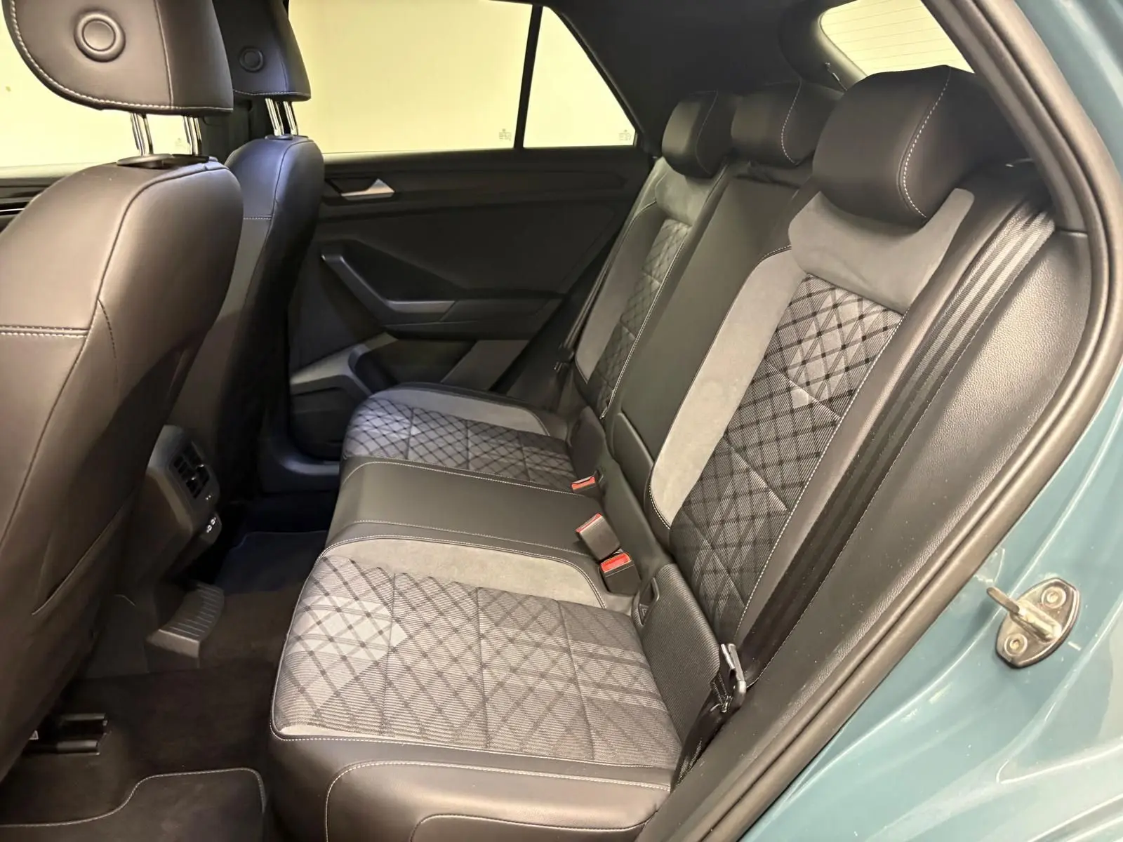 Vue côté droit de l'intérieur arrière du Volkswagen T-Roc 2024 bleu pétrole avec sièges en cuir et tissu à motifs géométriques.