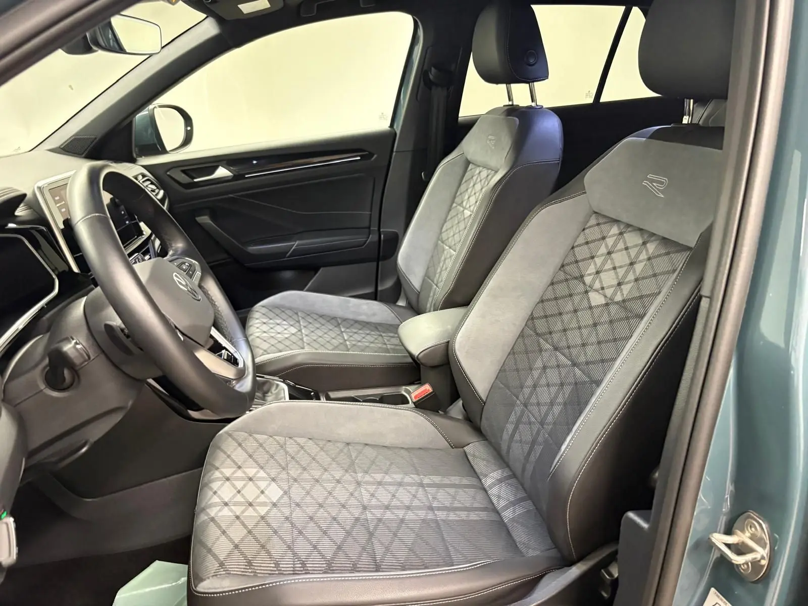 Vue intérieure côté conducteur du Volkswagen T-ROC 1.5 TSI R-Line 2024 avec sièges en tissu et cuir gris à motifs géométriques