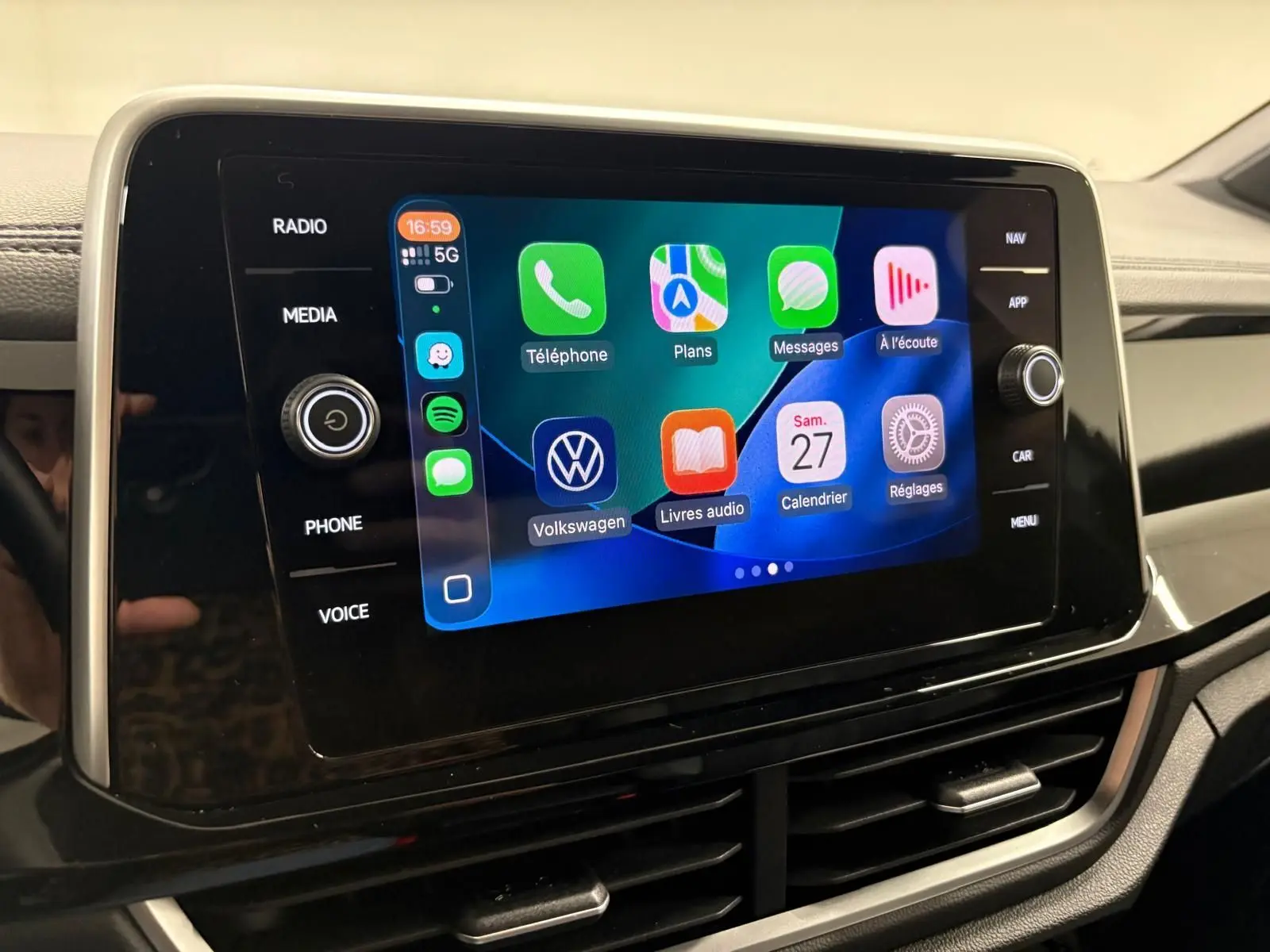 Écran tactile central du Volkswagen T-Roc 2024 affichant l'interface Apple CarPlay avec commandes autour.