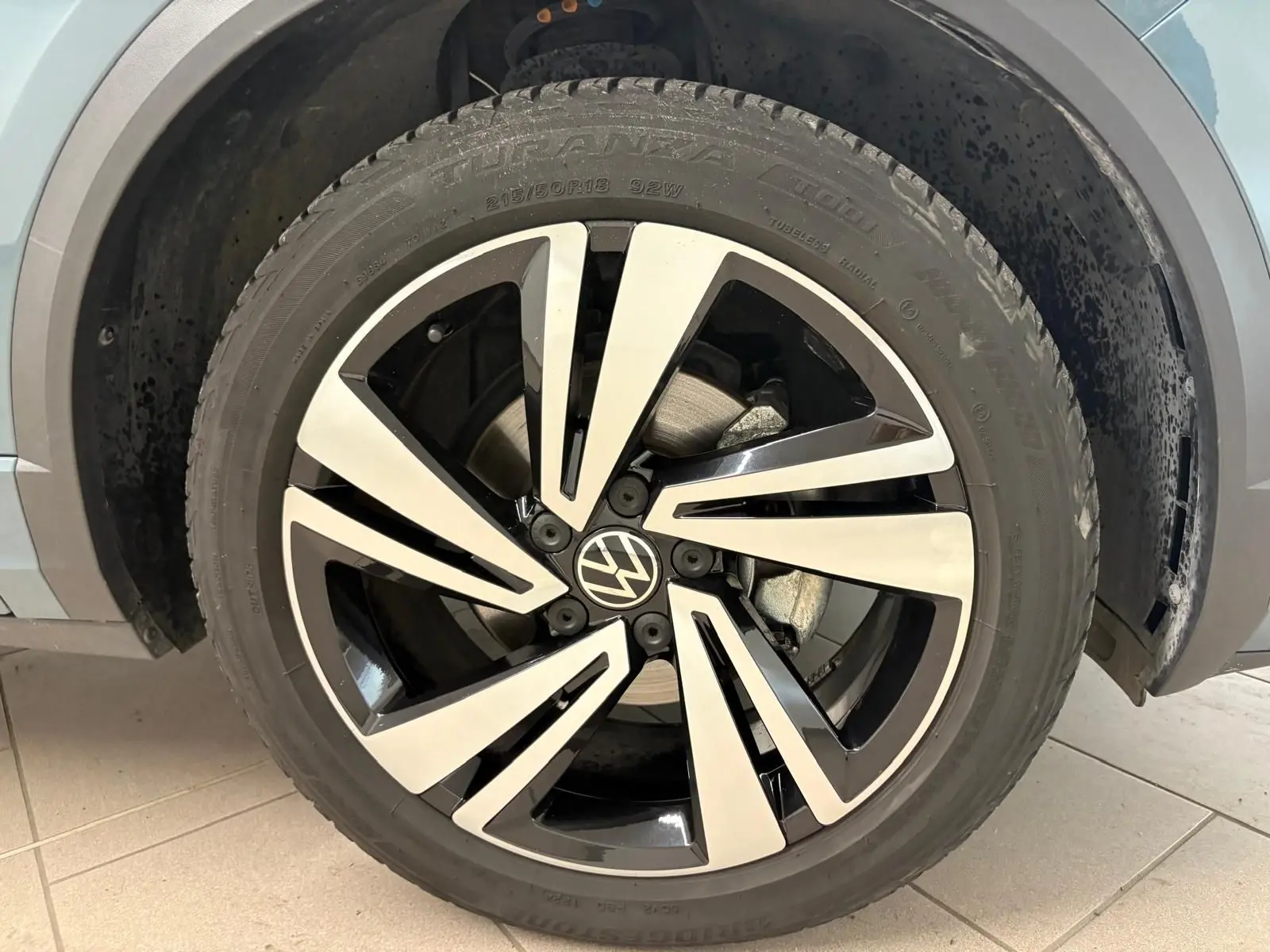 Gros plan sur la jante alliage bicolore du Volkswagen T-Roc bleu pétrole, version R-Line 2024, côté roue avant droite.