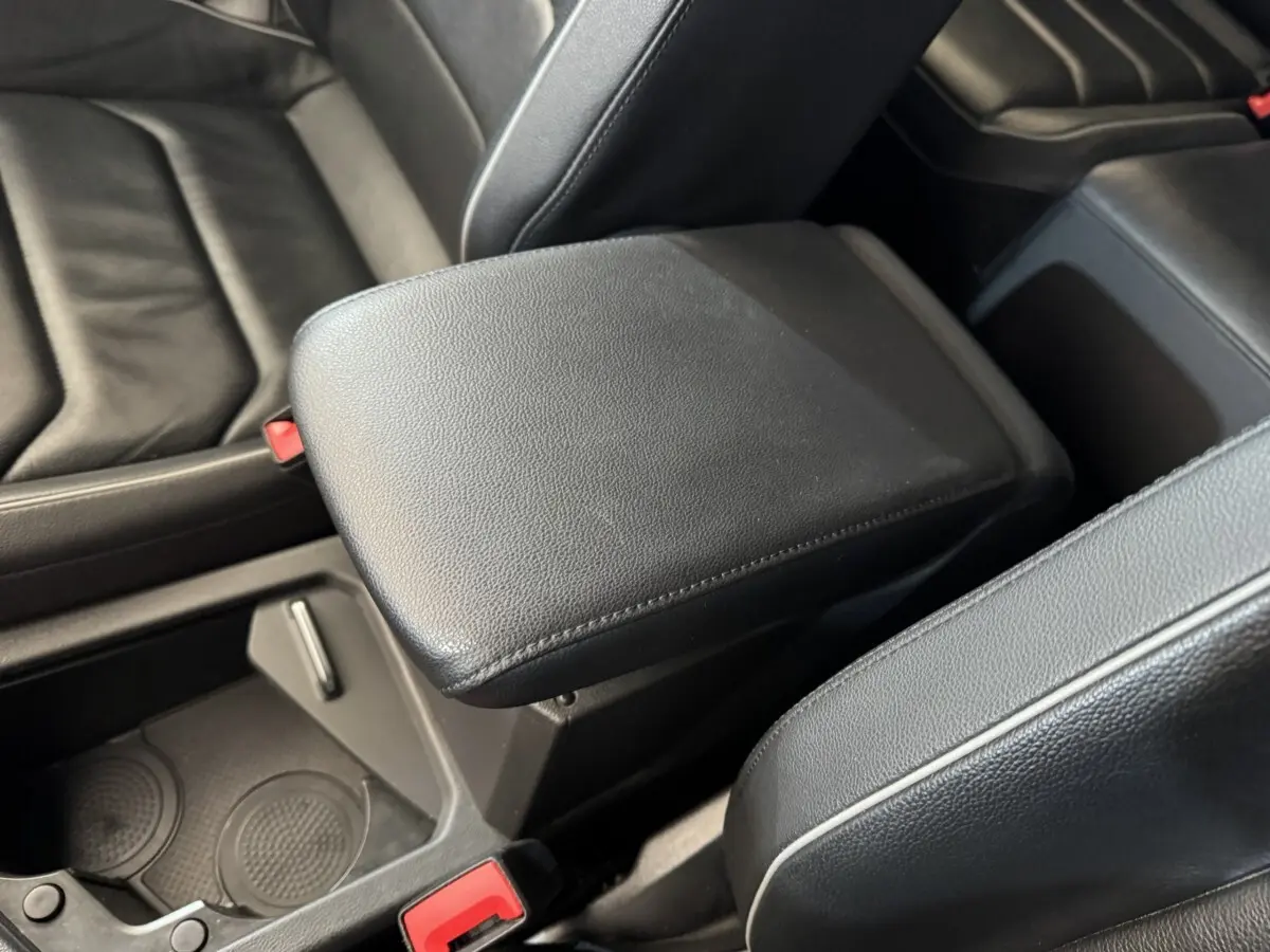Gros plan sur l'accoudoir central noir en cuir entre les sièges avant du Volkswagen Tiguan Allspace gris foncé.