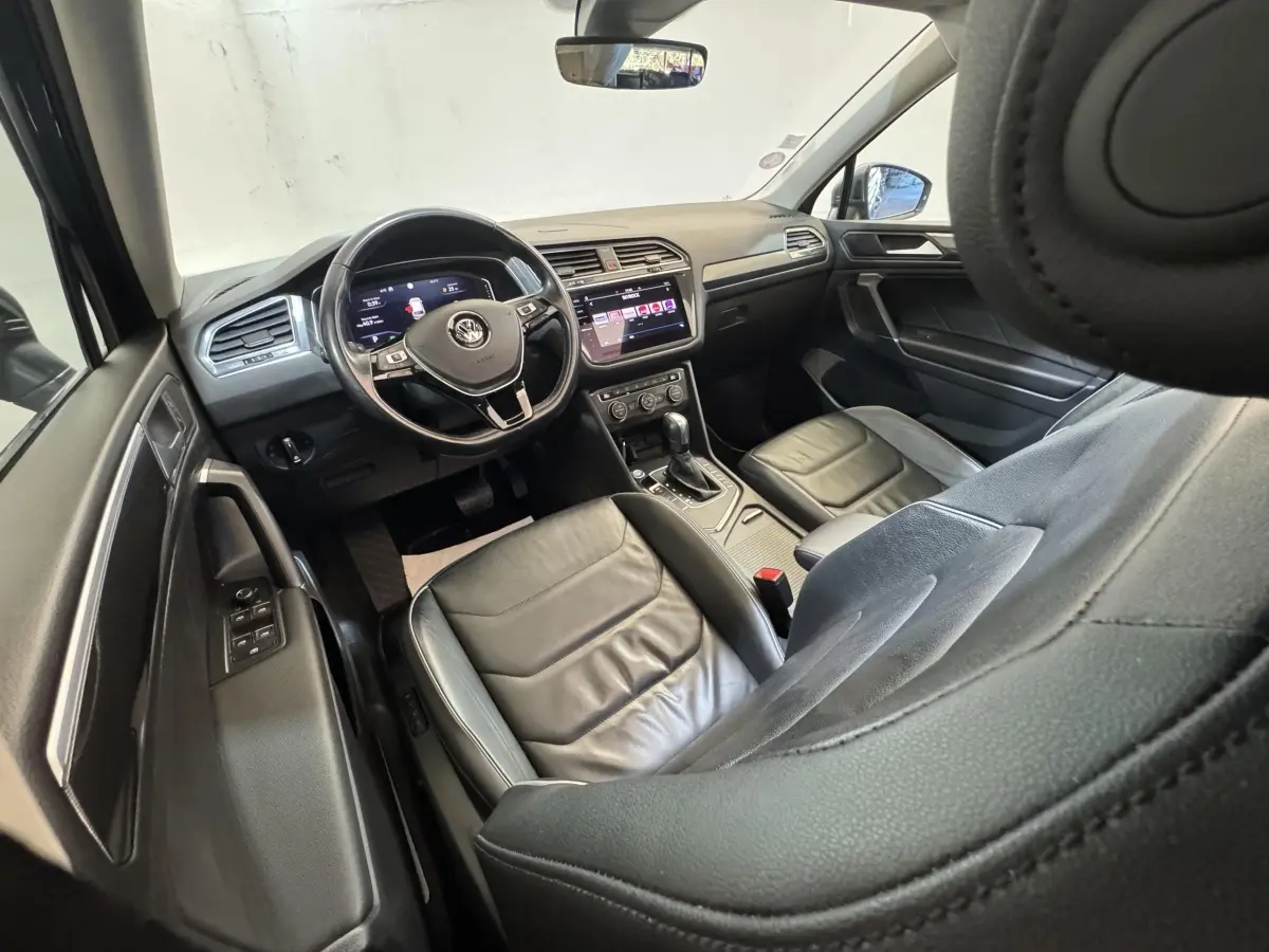 Vue intérieure côté conducteur du Volkswagen Tiguan Allspace 2019, sièges cuir noirs et tableau de bord digital.