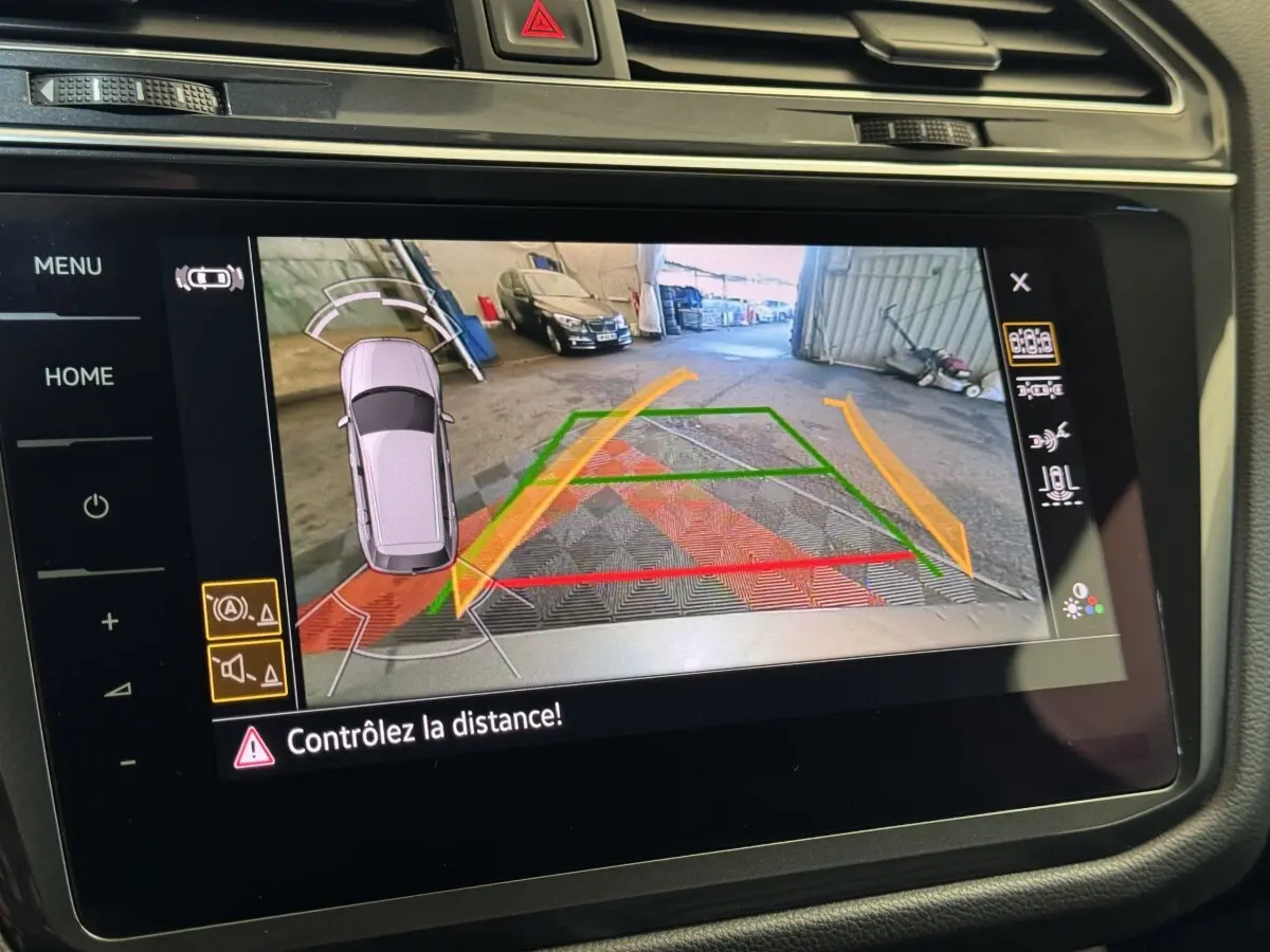 Vue écran multimédia du Volkswagen Tiguan Allspace gris foncé en marche arrière avec caméra de recul et guidage de trajectoire.