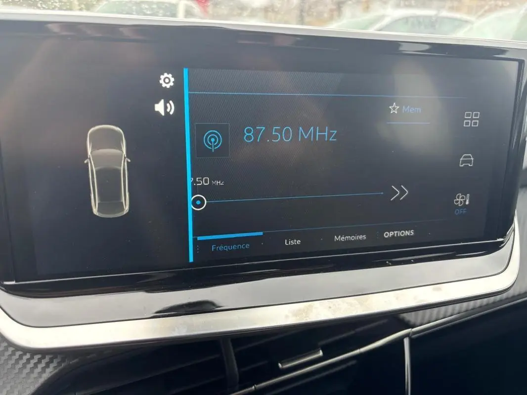 Écran tactile du cockpit numérique de la Peugeot 208 Hybrid 100 e-DCS6 Style gris, affichant la radio à 87,50 MHz.