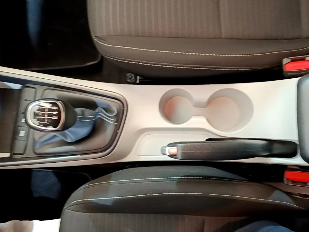 Vue plongeante sur la console centrale beige et noire avec levier de vitesse manuel et frein à main d'une Hyundai i20 gris clair.