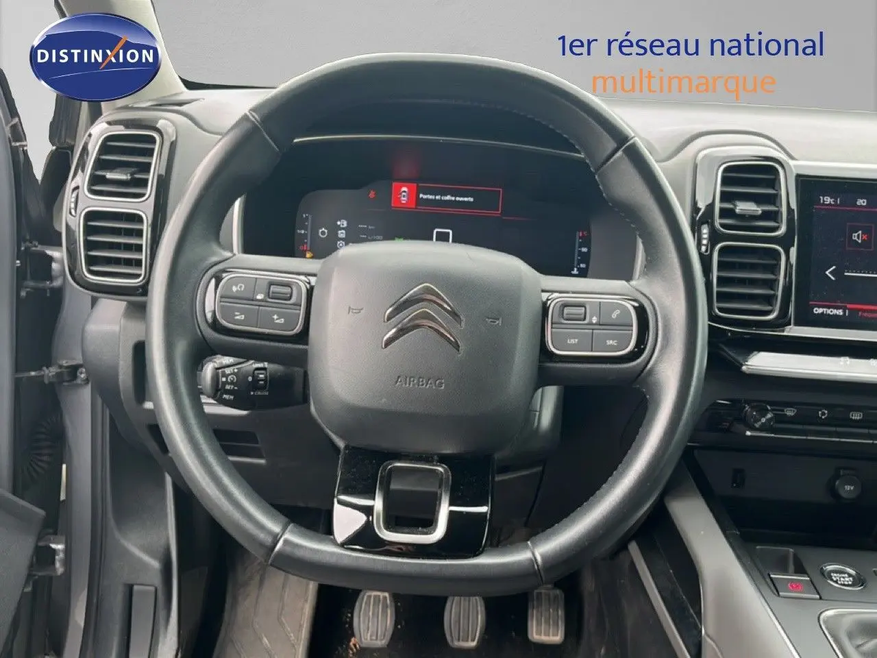 Vue frontale du volant noir et du tableau de bord numérique d’un Citroën C5 Aircross gris clair métal de 2020.