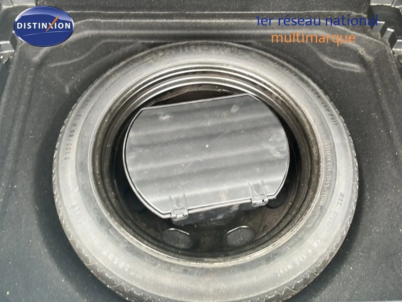 Pneu de secours monté dans le coffre d'une Citroën C5 Aircross gris clair métal, vue en plongée.