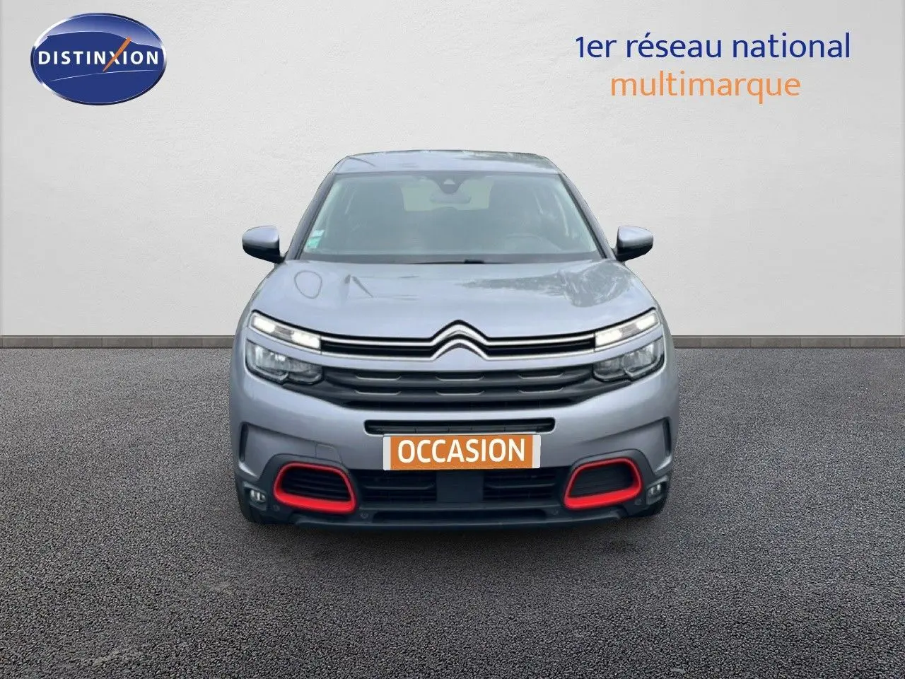 Vue avant d'un Citroën C5 Aircross gris clair métal avec détails rouges sur le pare-chocs et calandre distinctive.