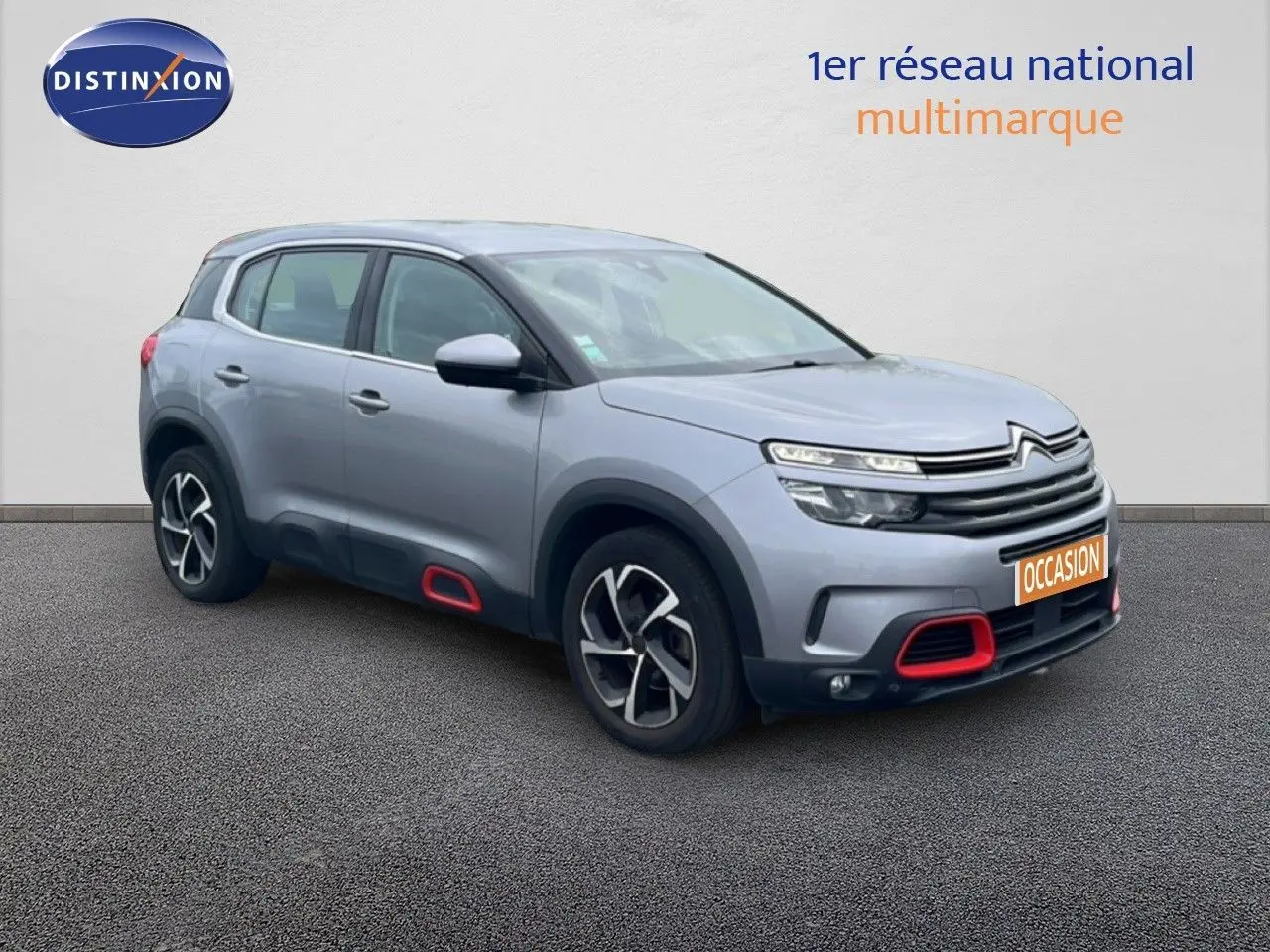 Citroën C5 Aircross gris clair métal en 3/4 avant droit avec détails rouges sur boucliers et bas de caisse.