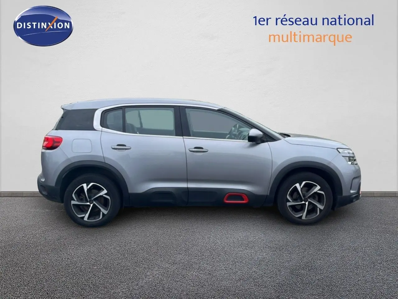 Profil droit d'un Citroën C5 Aircross gris clair métallisé avec jantes noires et détails rouges sur bas de caisse.