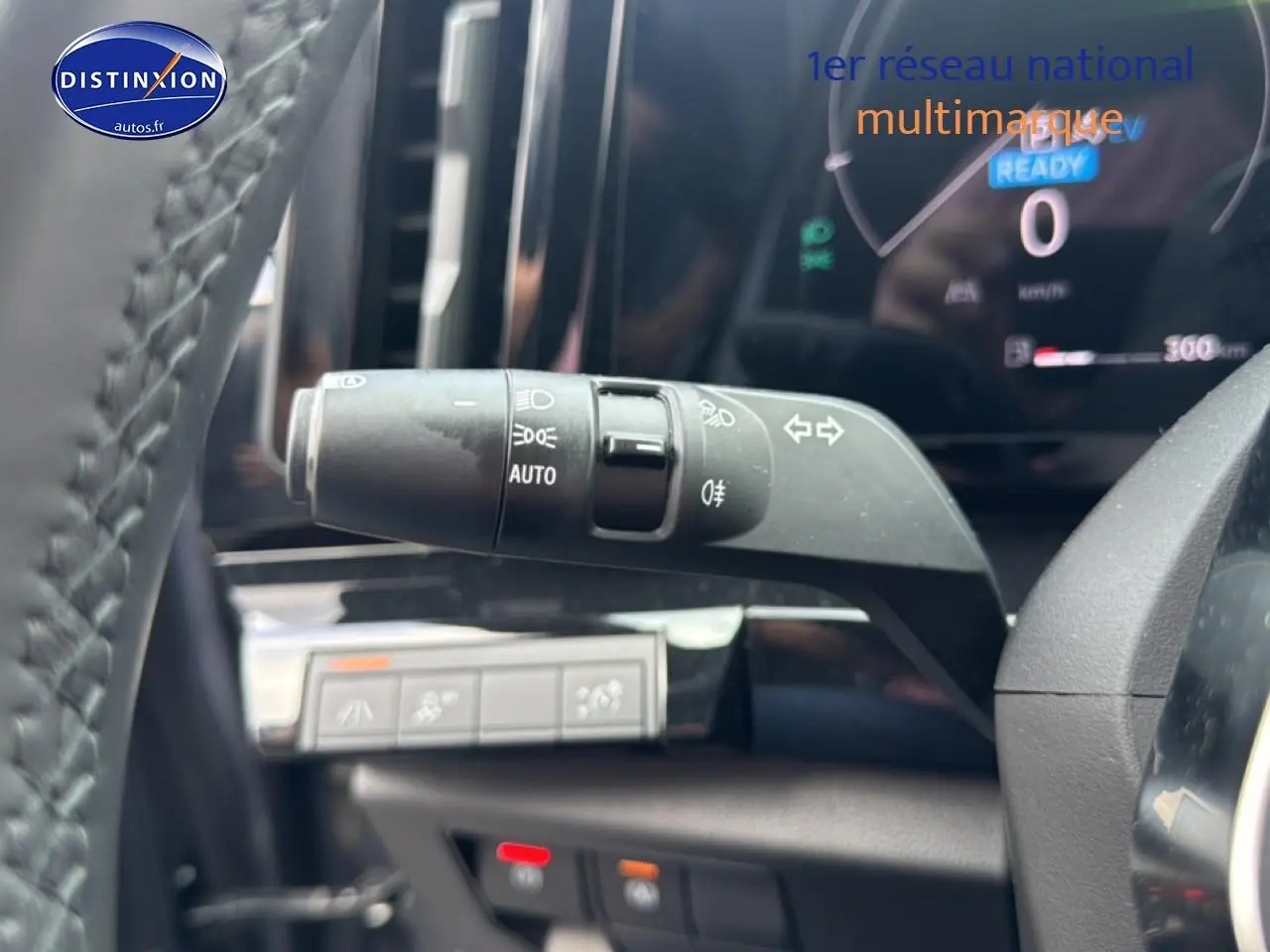 Gros plan sur la commande des phares automatiques dans l’habitacle gris du Renault Austral 2024 hybride.