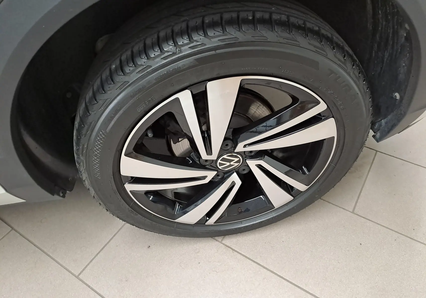Gros plan sur la jante alliage bicolore du Volkswagen T-Roc 1.5 TSI 150 DSG7 R-Line gris Ascot, côté avant droit.