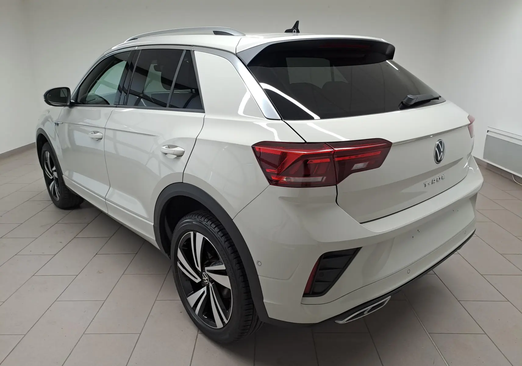 Vue 3/4 arrière droite du Volkswagen T-Roc 2024 en gris Ascot, avec jantes R-Line et vitres teintées.