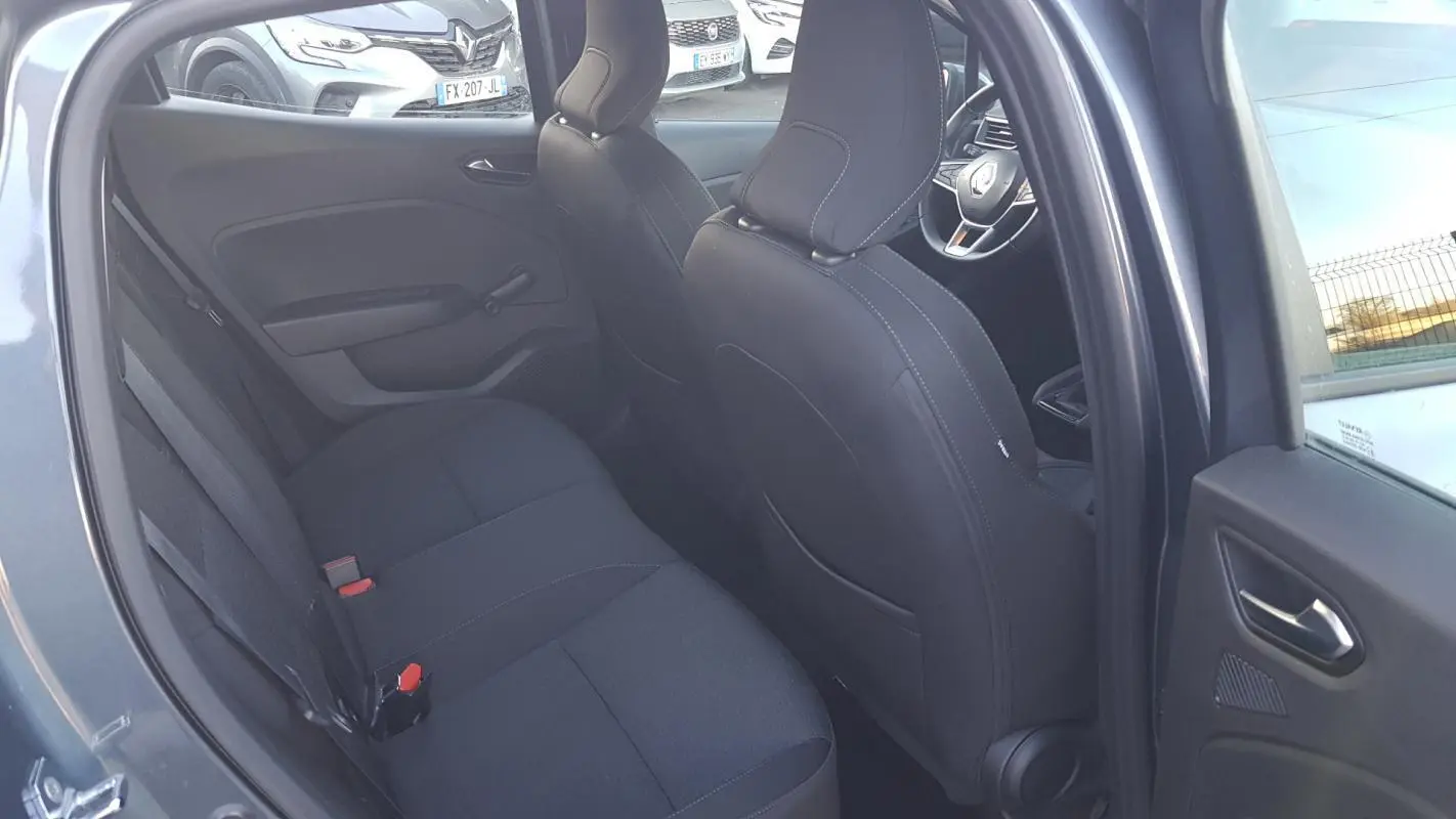 Vue intérieure côté gauche montrant les sièges arrière noirs et l'avant d'une Renault Clio gris 2021.