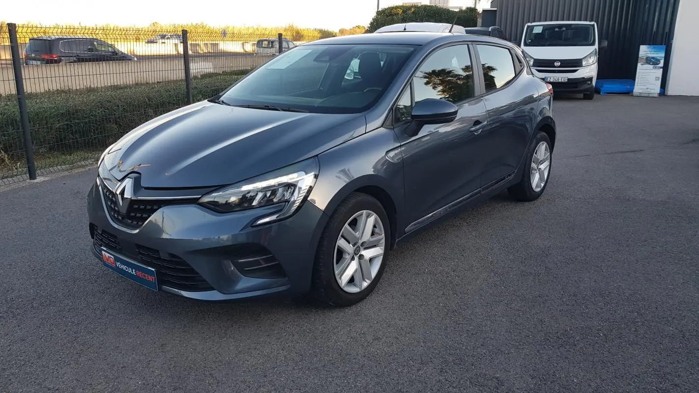 Renault Clio gris 2021 vue 3/4 avant droit, avec phares LED allumés et jantes alliage cinq branches.