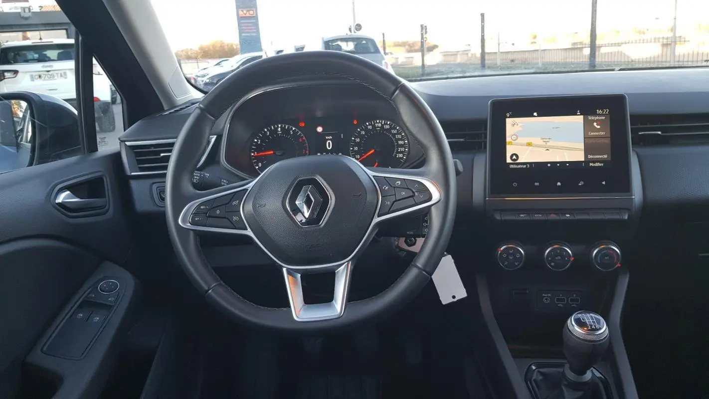 Vue intérieure frontale du poste de conduite de la Renault Clio gris 2021 avec volant multifonction et écran tactile central.