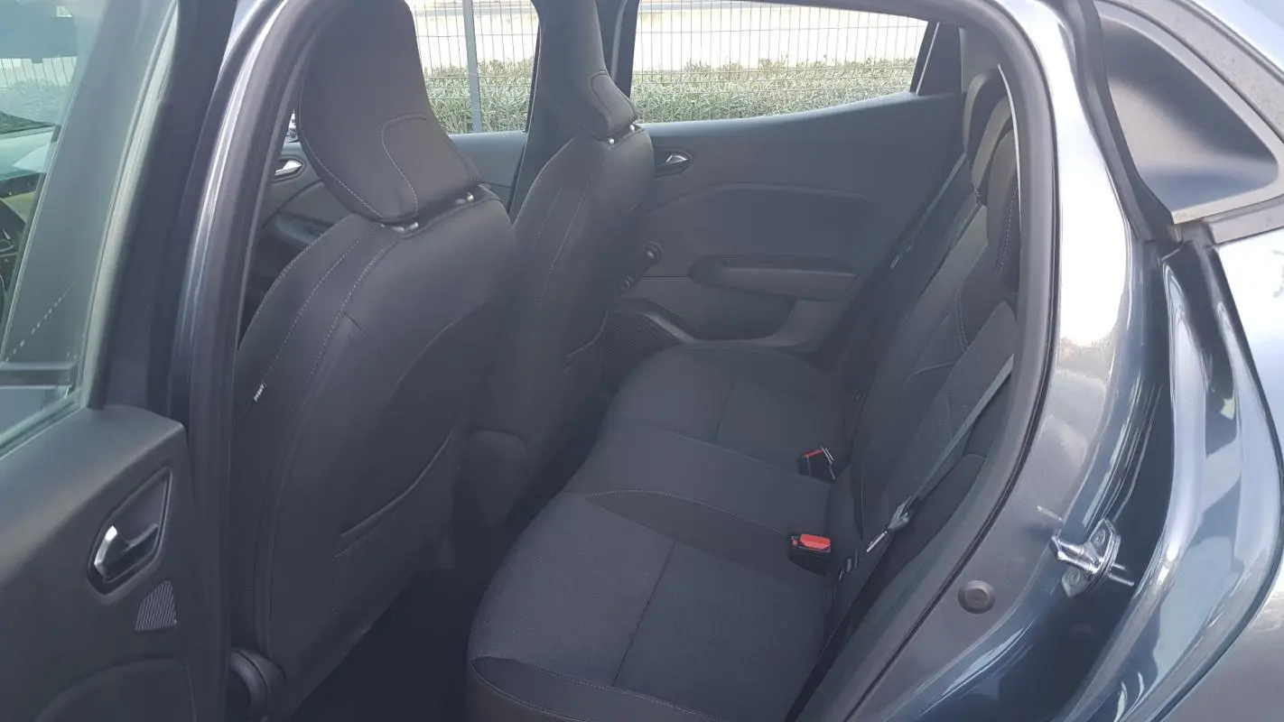 Vue intérieure côté arrière droit d'une Renault Clio gris, montrant les sièges arrière en tissu noir.