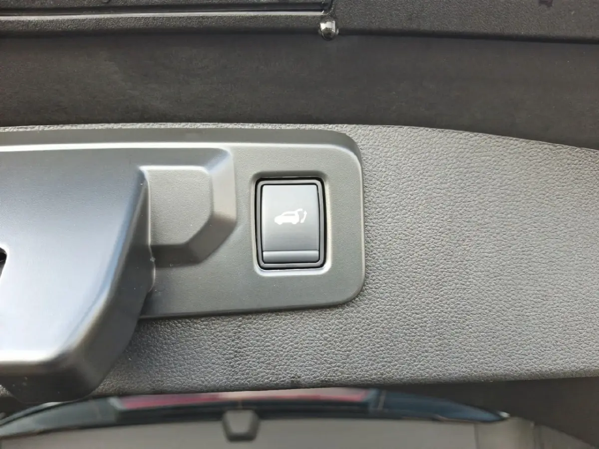 Gros plan sur le bouton d'ouverture électrique du coffre dans l'intérieur noir du Renault Symbioz Iconic E-Tech 2025.