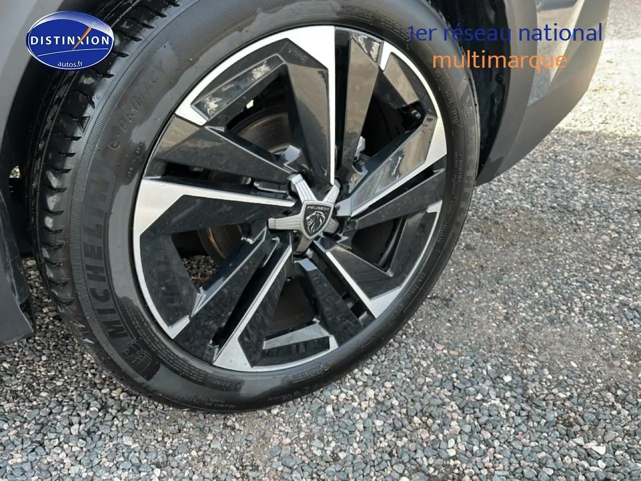 Gros plan sur la jante alu noire et argentée d'une Peugeot 408 Hybrid 145 allure gris sélénite, roue avant droite.