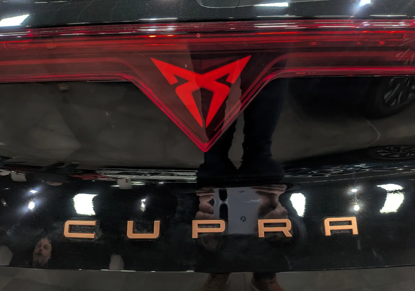 Gros plan sur le logo rouge et l'inscription CUPRA en bronze sur la malle arrière noire Minuit du Formentor eHybrid 2025.