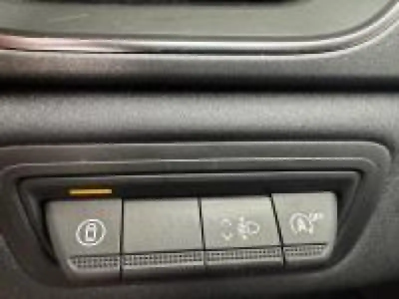Gros plan sur les commandes de fonctions d’aide à la conduite dans l’habitacle d’un Renault Captur rouge.