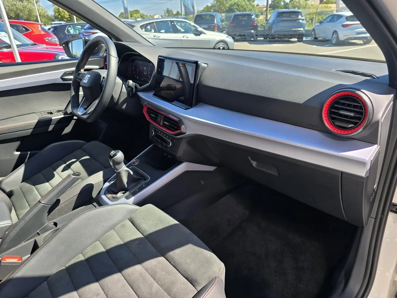 Vue intérieure côté passager du SEAT Arona 2024 avec sellerie suédine noire, volant sport et console centrale moderne.