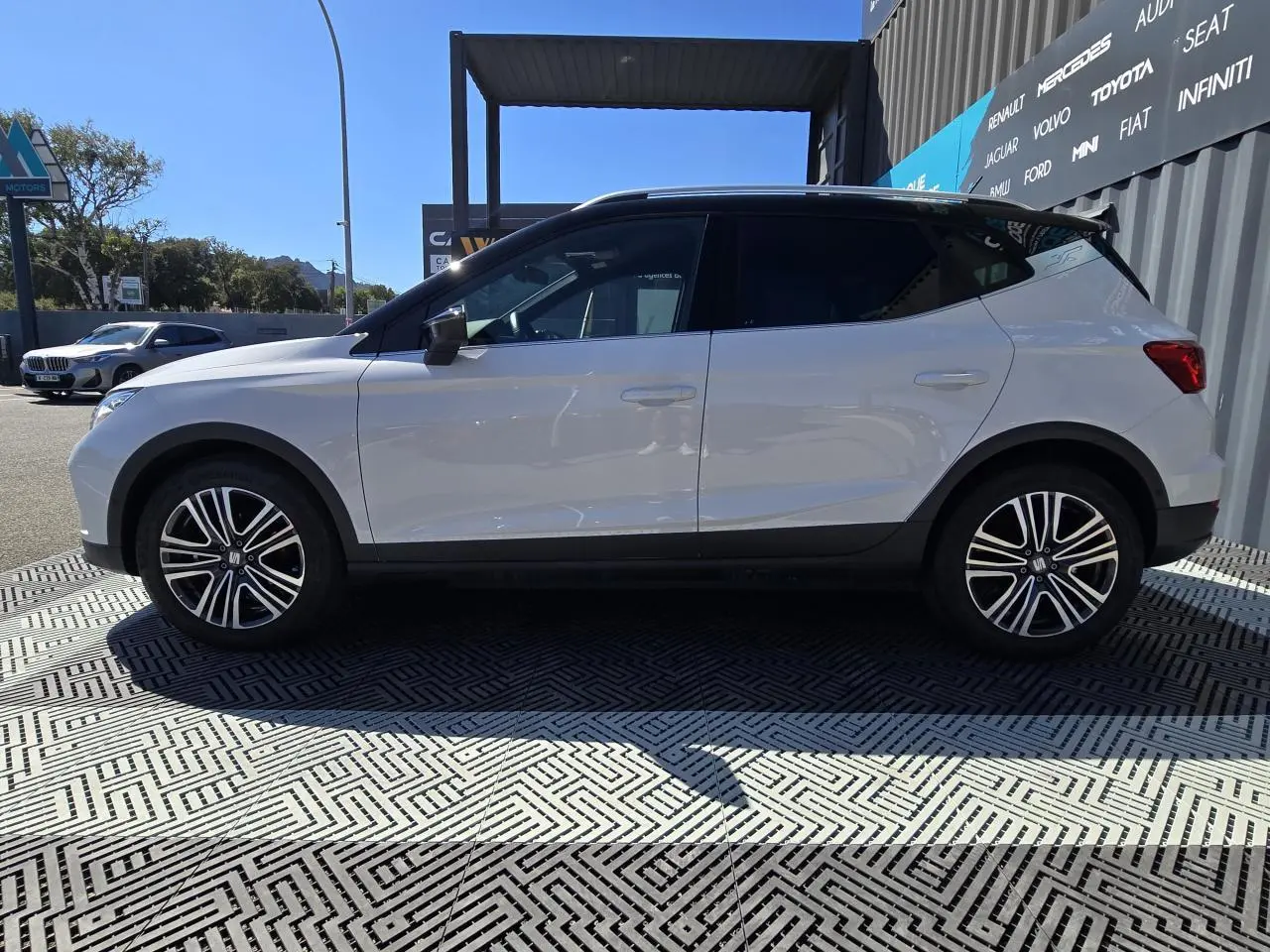 Vue de profil côté gauche du SEAT Arona 2024 blanc avec toit noir et jantes alliage 17 pouces.