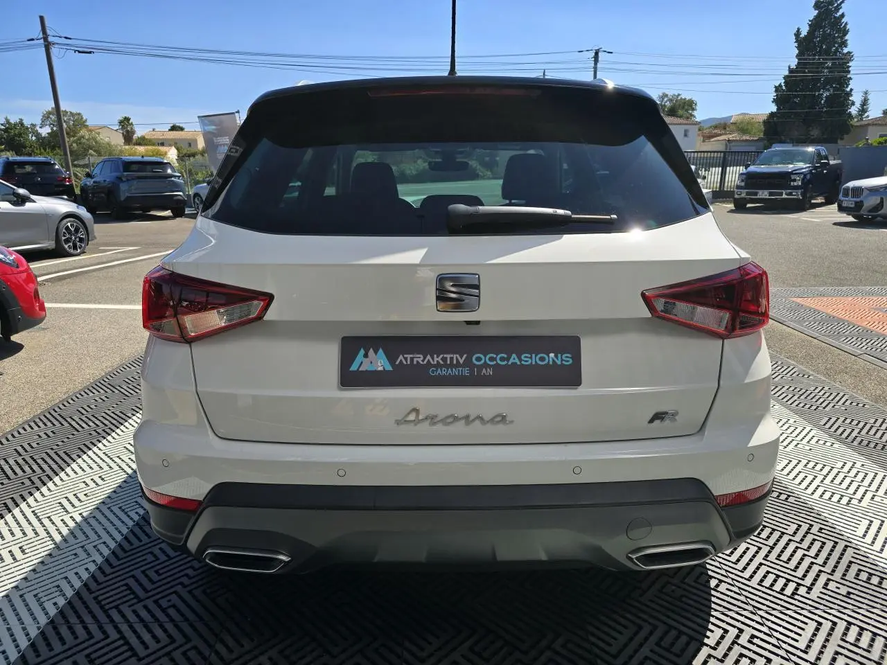 Vue arrière d'un SEAT Arona blanc avec toit noir, badge FR et double sortie d'échappement chromée.
