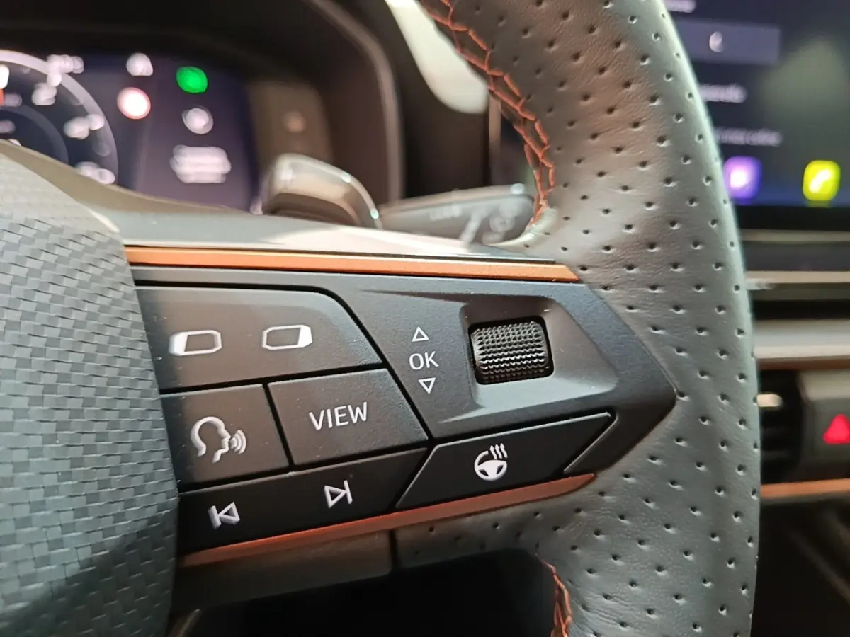 Gros plan sur le volant cuir perforé noir du CUPRA Formentor 2024, avec commandes multifonctions et surpiqûres orange.