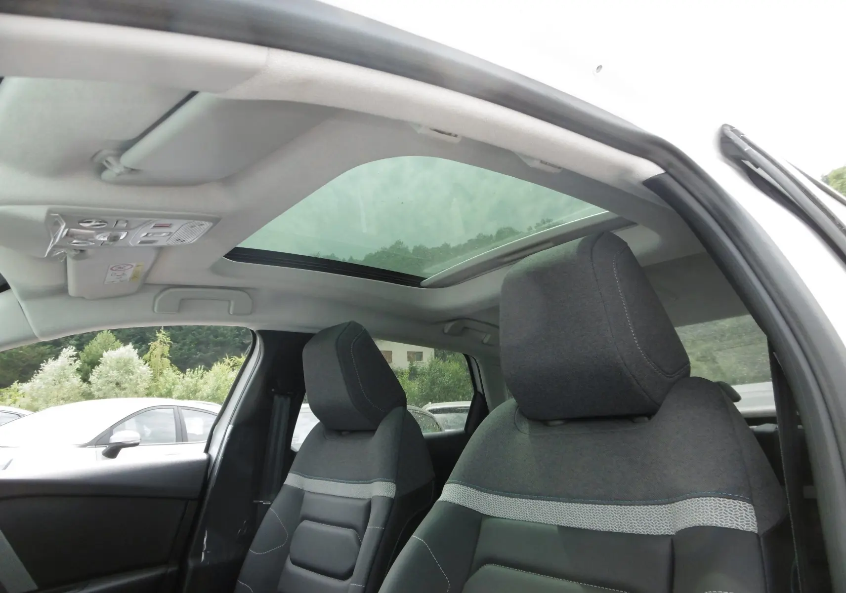 Vue intérieure du toit panoramique et des sièges avant gris foncé de la Citroën C4 X blanc polaire 2023.