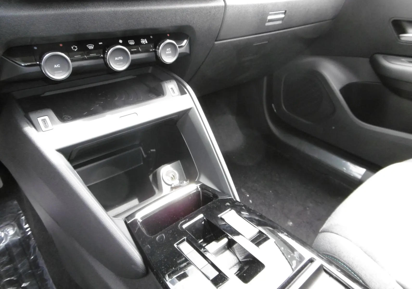 Vue rapprochée de la console centrale noire du Citroën C4 X 2023 avec commandes climatisation et rangement ouvert.