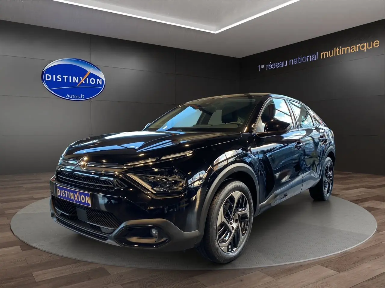 Vue 3/4 avant droite d'une Citroën C4 BlueHDi 130 Plus noire Perla Nera avec jantes alliage et calandre distinctive.