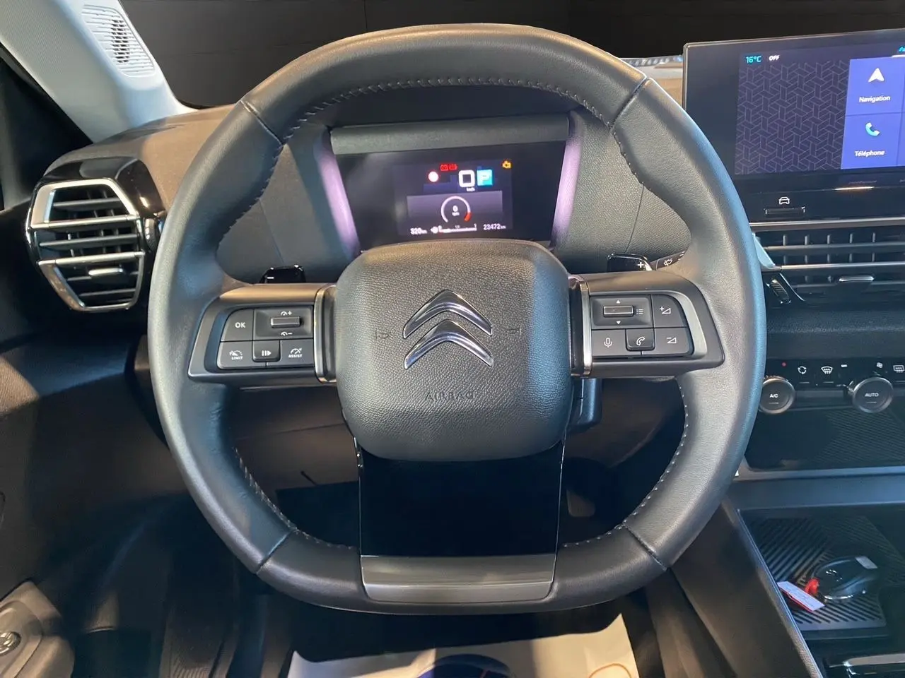 Vue frontale du volant noir de la Citroën C4 BlueHDi 130 Plus 2023 avec commandes intégrées et tableau de bord numérique.