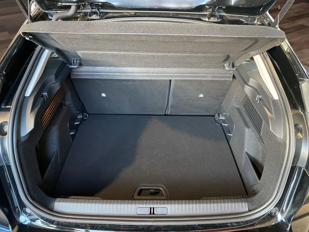 Coffre ouvert d'une Citroën C4 Noir Perla Nera 2023, vue plongeante sur l'espace de chargement vide et propre.