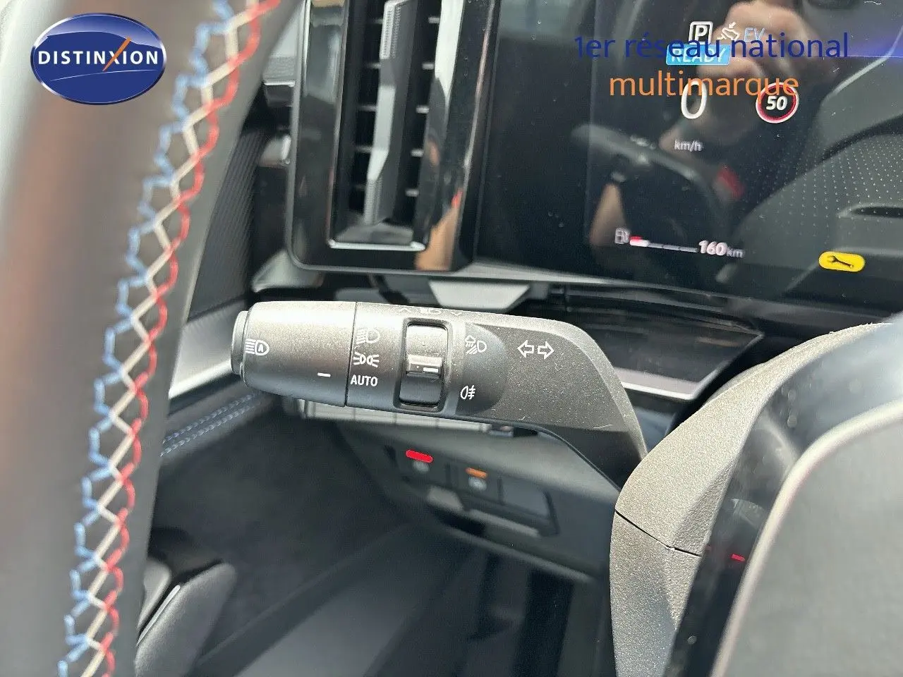 Gros plan sur la manette de clignotants du tableau de bord d'un Renault Austral 2024 bleu iron avec volant surpiqué.