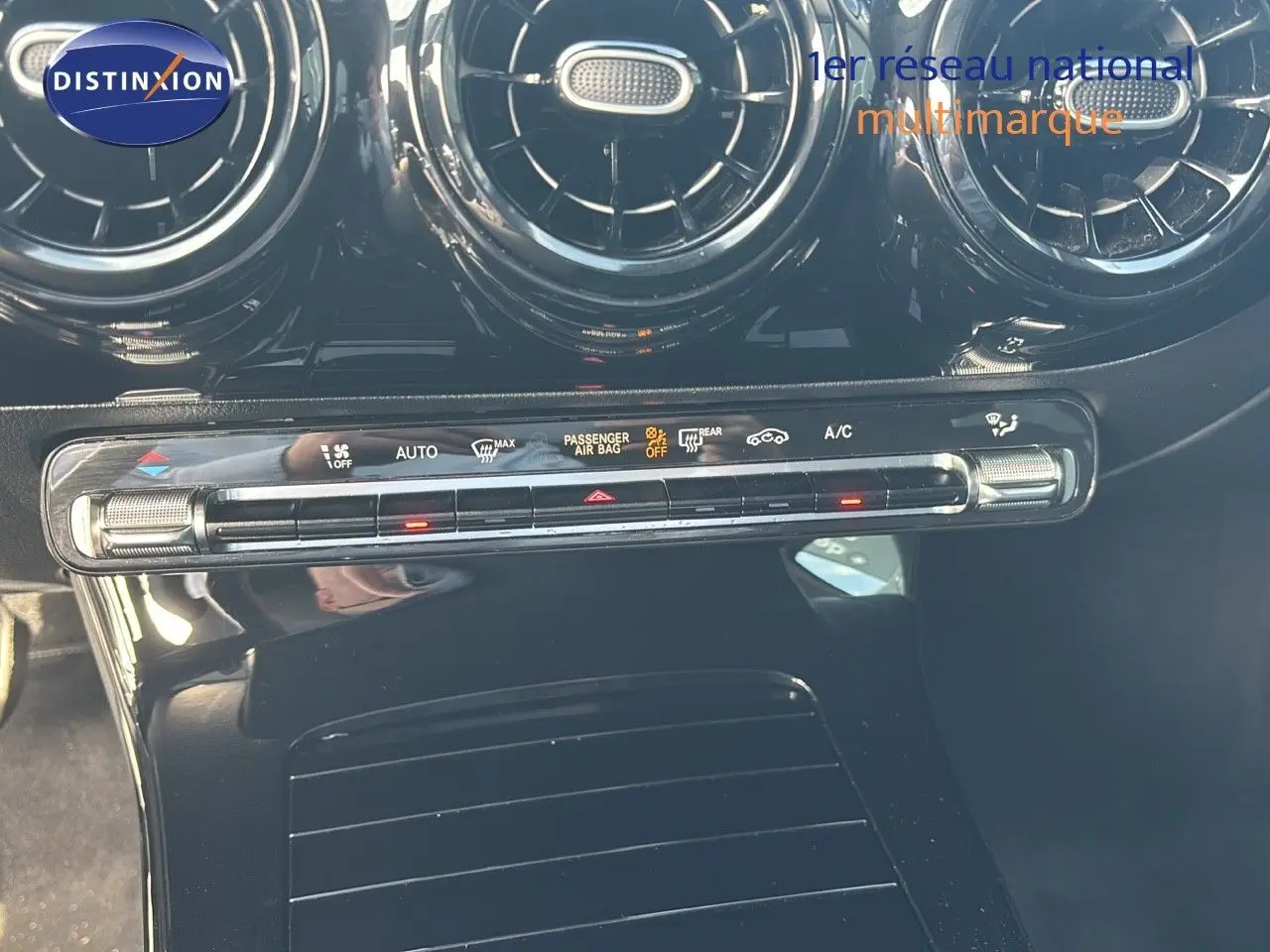 Vue rapprochée de la console centrale noire brillante avec commandes climatisation et aérateurs ronds d’une Mercedes Classe A 200D.
