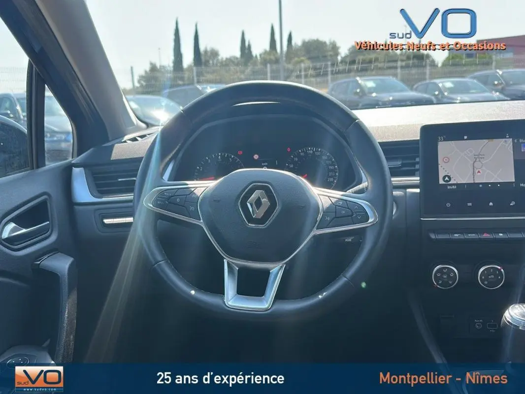 Vue intérieure centrée sur le volant du Renault Captur gris 2022 avec tableau de bord et écran tactile visible.