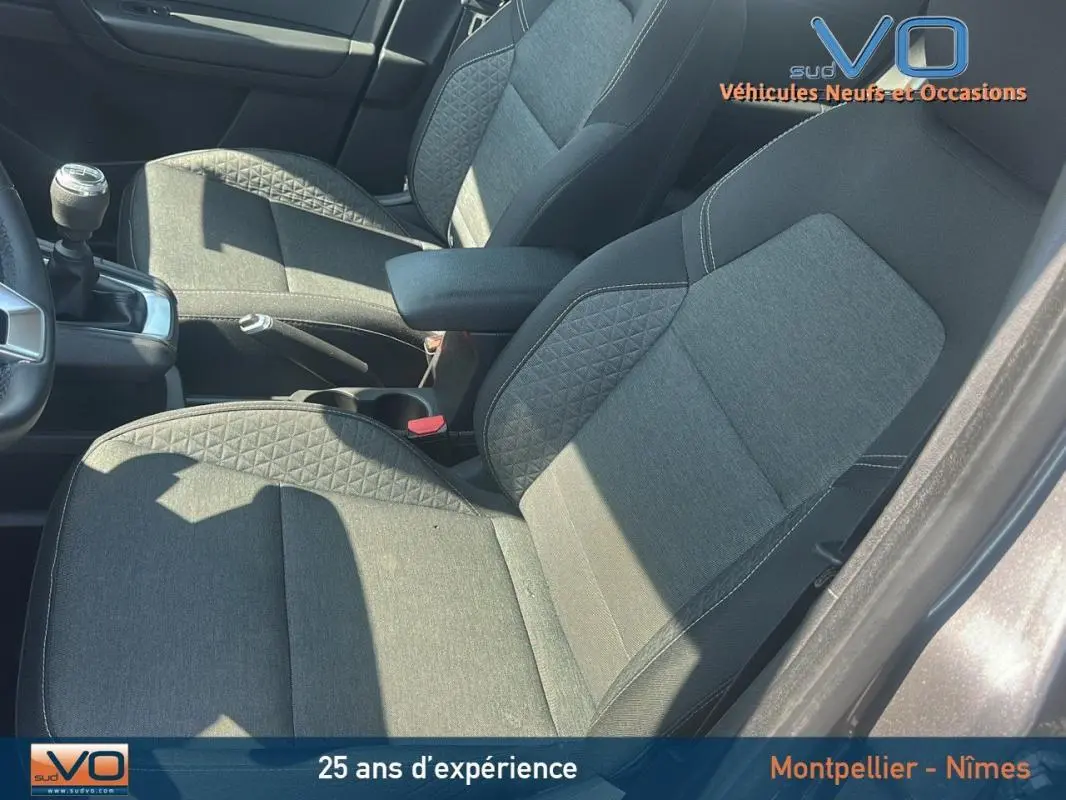 Vue intérieure côté conducteur du Renault Captur gris 2022, montrant les sièges tissu et la boîte manuelle.