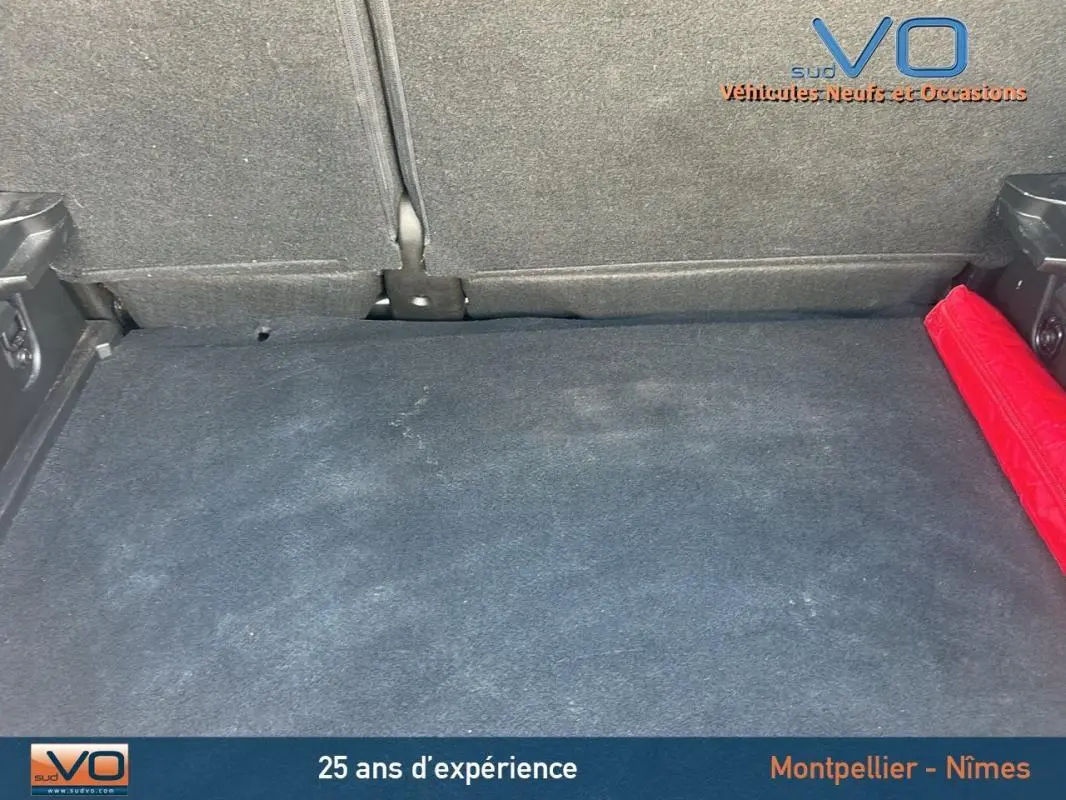 Coffre spacieux du Renault Captur gris TCe 90 Business 2022, avec tapis noir et triangle de sécurité rouge sur le côté droit.