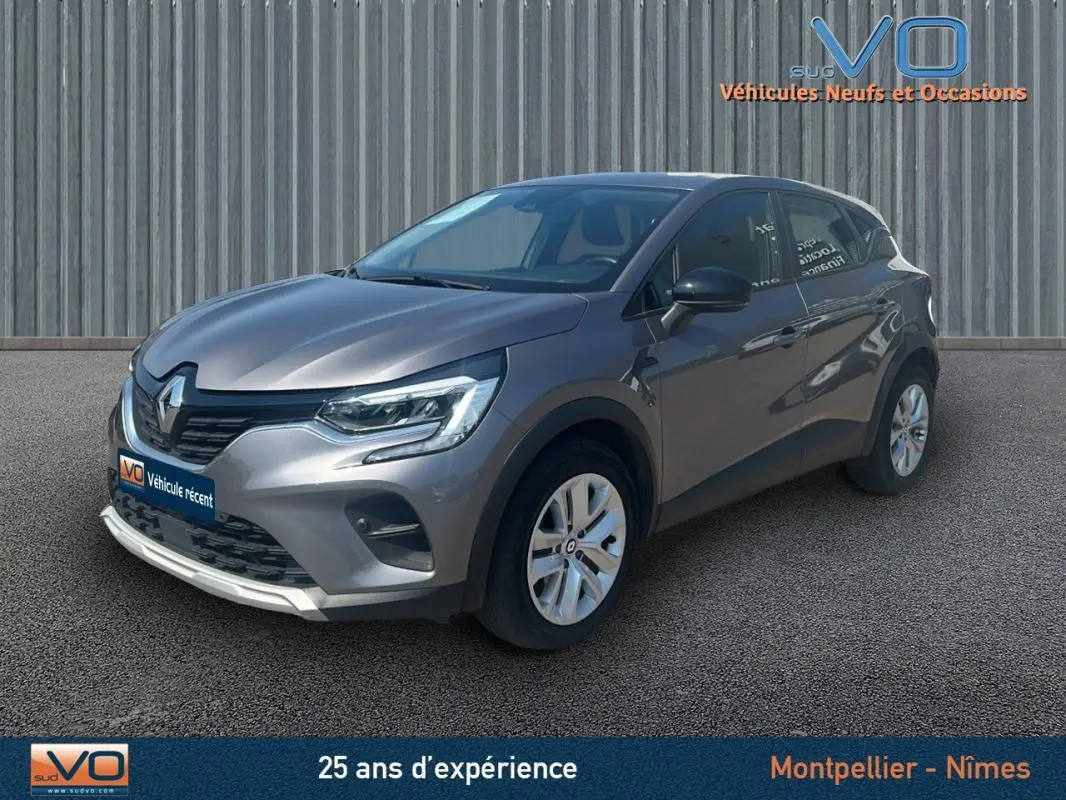 Renault Captur TCe 90 Business gris, vue 3/4 avant droit, avec jantes alliage et calandre noire brillante.
