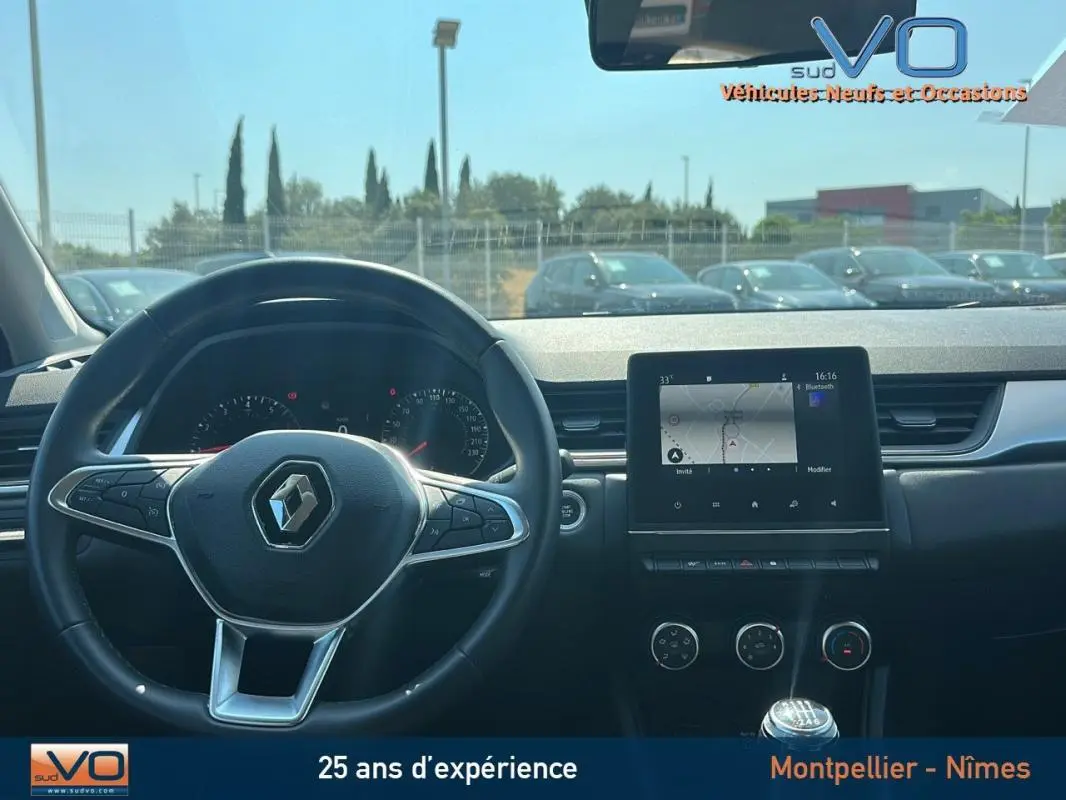 Vue intérieure du tableau de bord du Renault Captur gris 2022 avec écran tactile et volant multifonction.