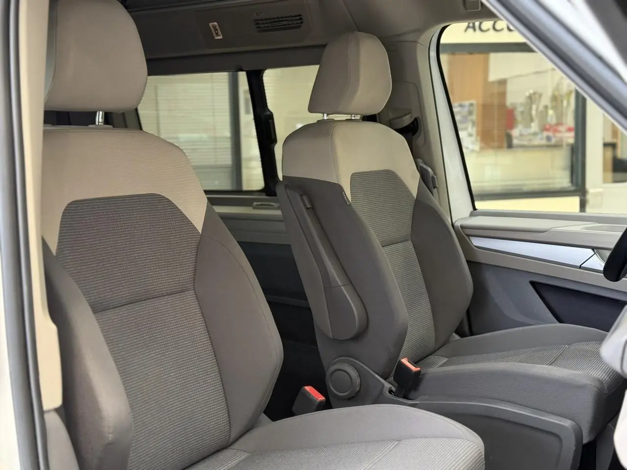 Vue intérieure côté droit des sièges avant gris clair et foncé du Volkswagen California T7 2024, avec accoudoirs et appui lombaire.