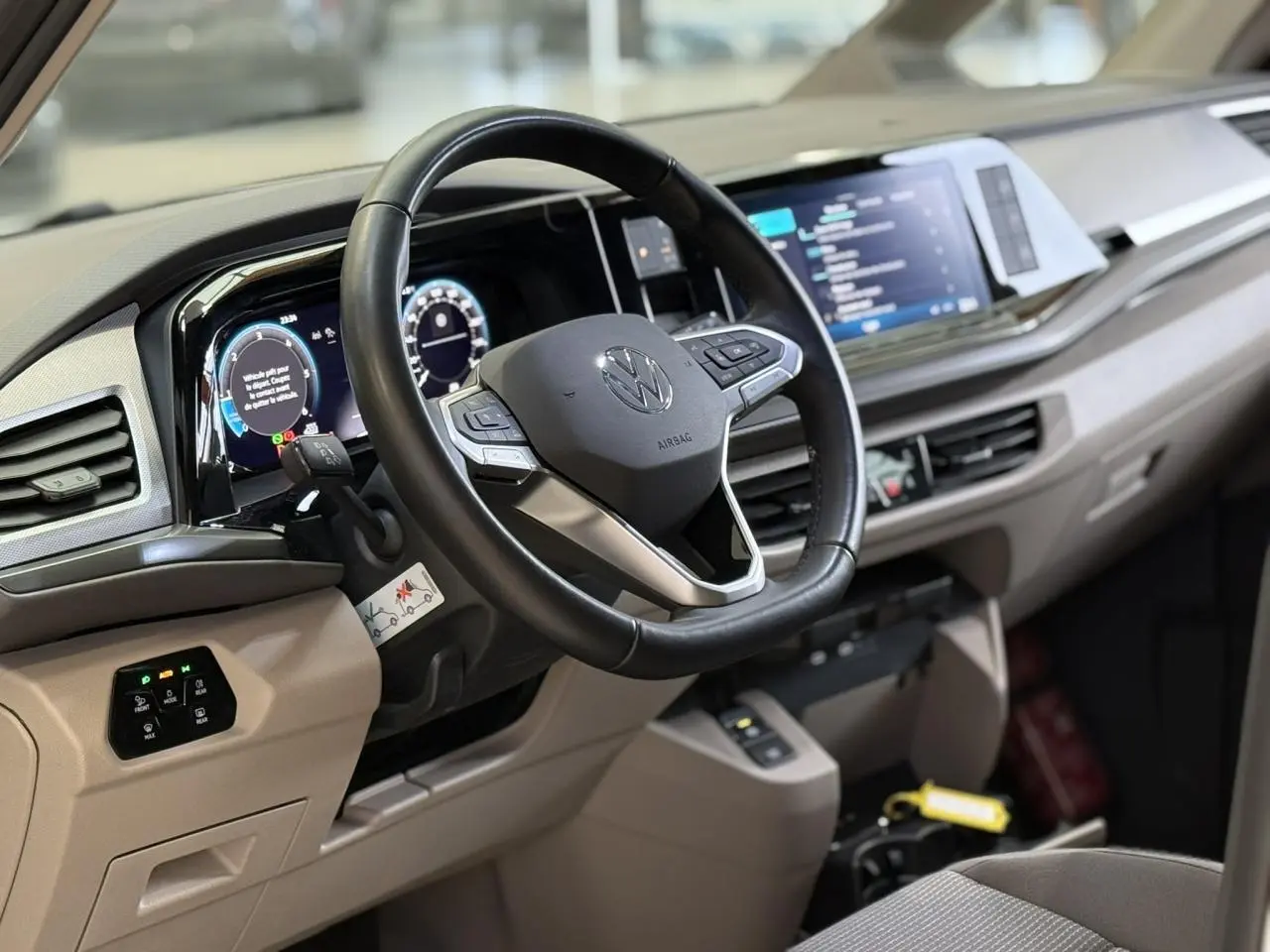 Vue intérieure côté conducteur du tableau de bord beige et volant cuir multifonction du Volkswagen California T7 2024.